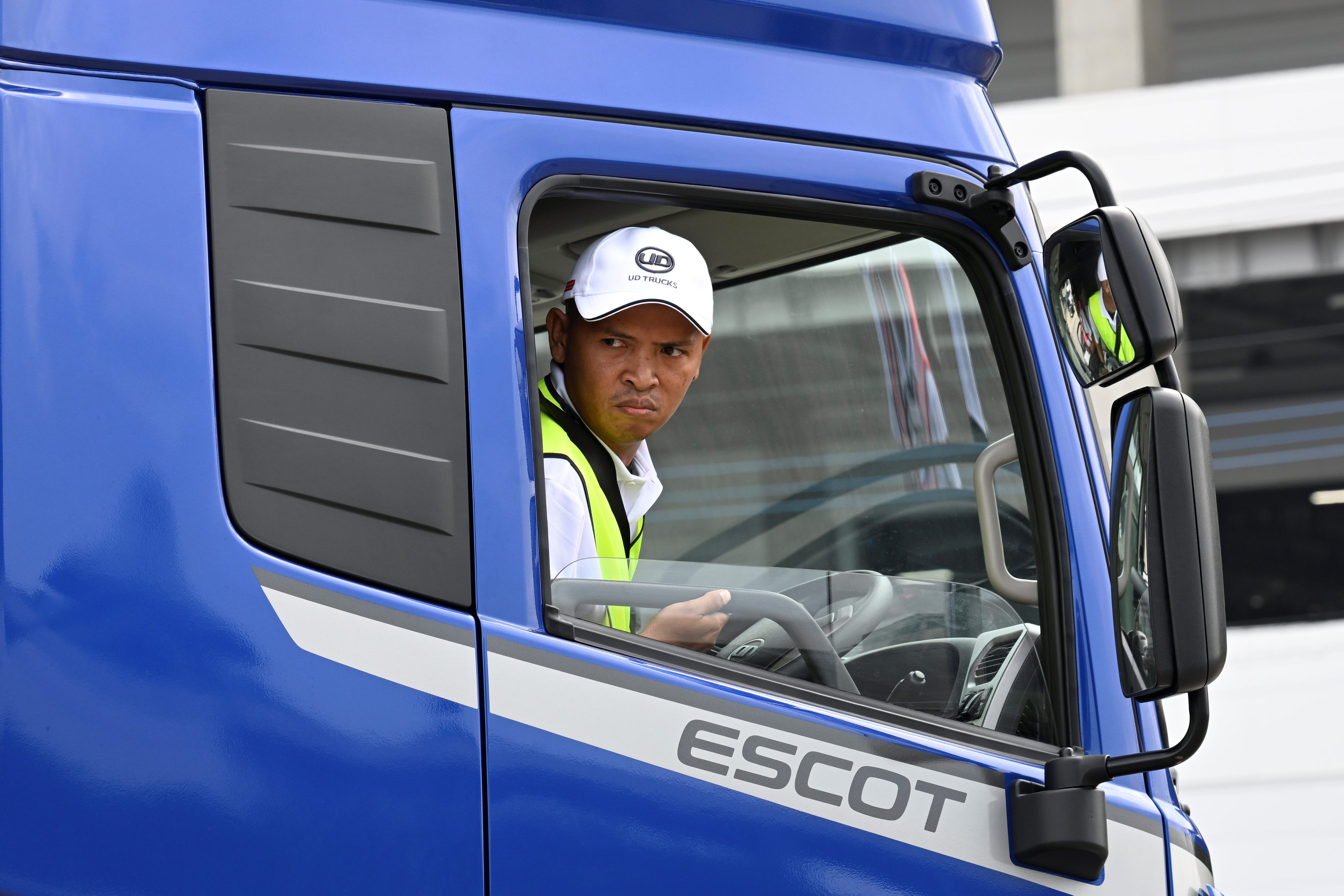 青いトラックの運転席に座る男性ドライバー