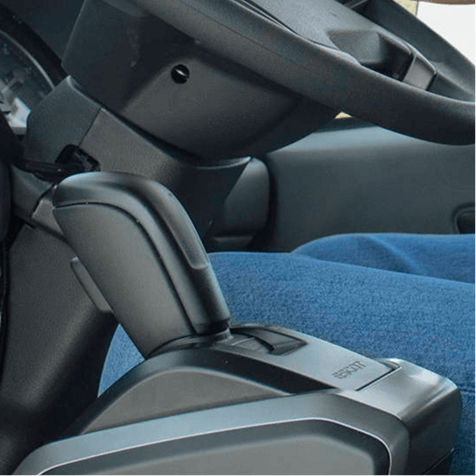 Cần số trên xe ô tô cạnh ghế tài xế, người mặc quần xanh.