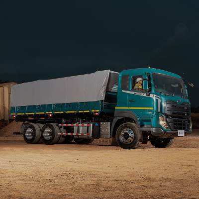 Groen vragmotor met seil oor vragte, staan op grondpad snags.