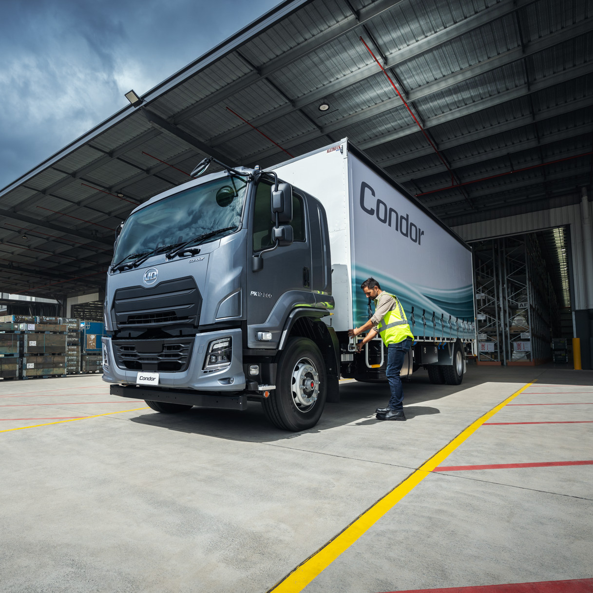 Man in hi-vis vest unloading a Condor truck at warehouse loading bay.