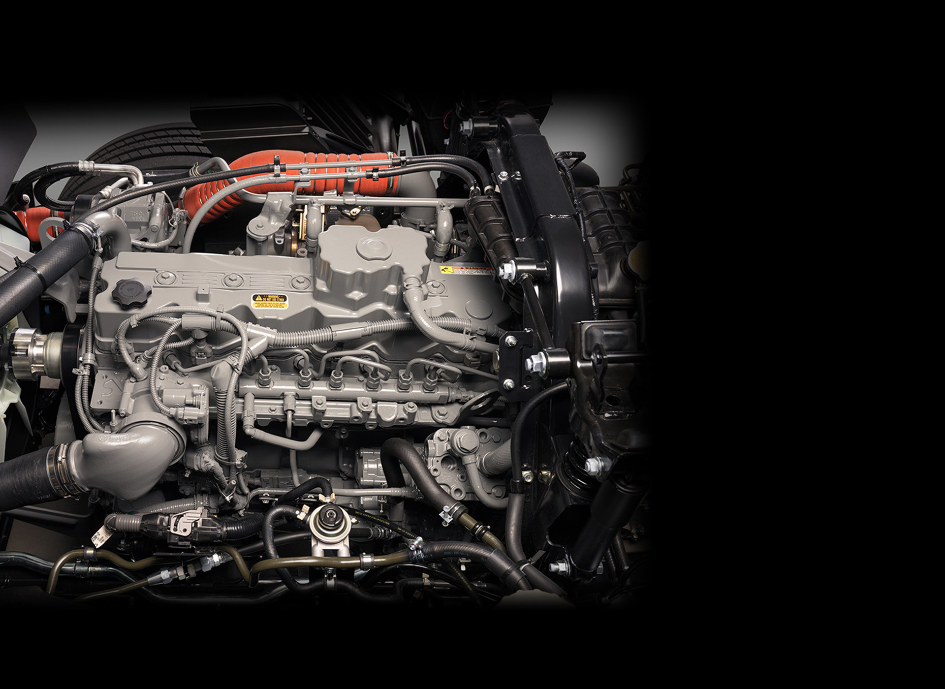 Close-up view of a car engine with metal pipes and wiring, black background.