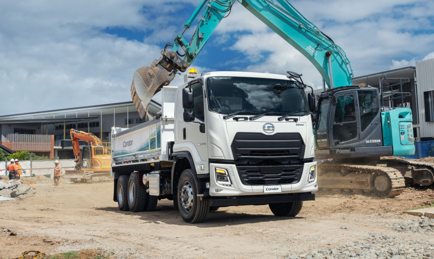 Excavator loading dirt into a white truck at a construction site