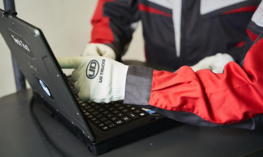 Person in gloves and red jacket using a laptop.