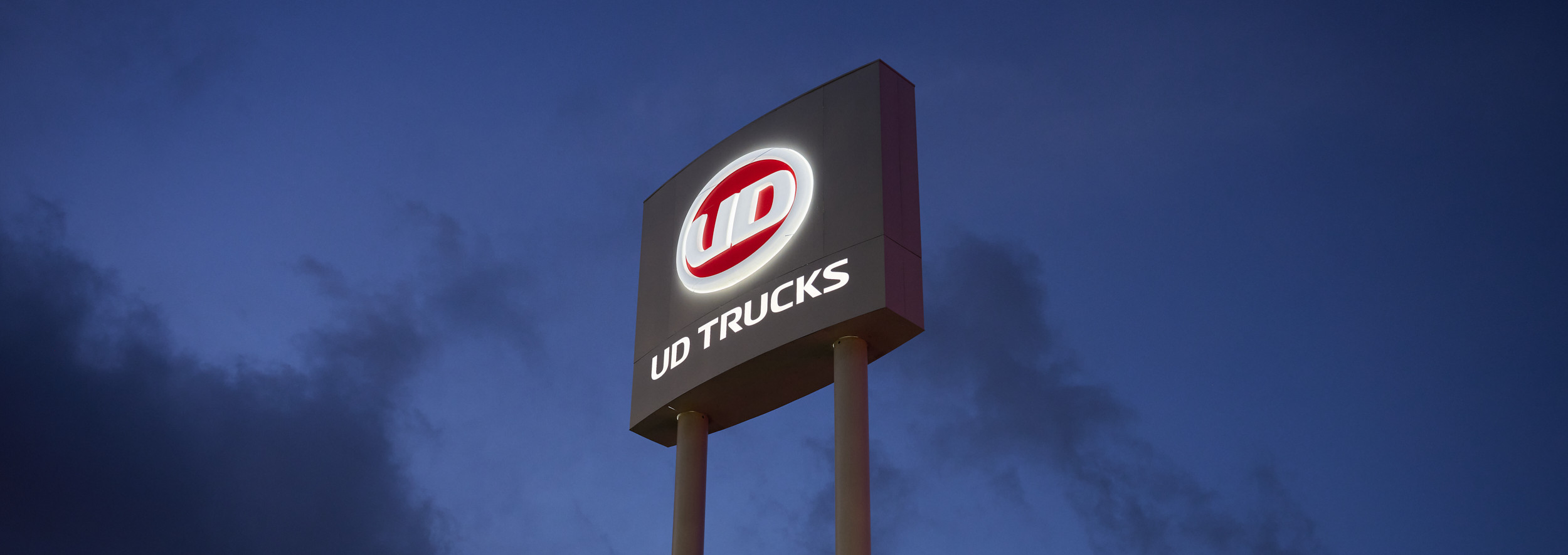 UD Trucks logo sign glowing against a dark evening sky - used trucks