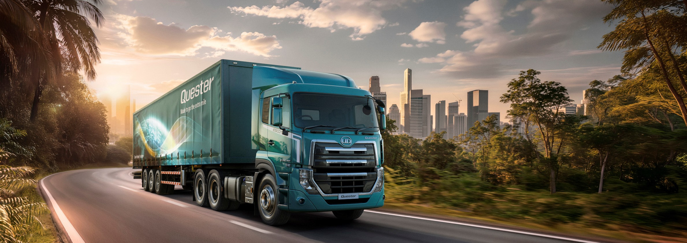 รถบรรทุกสีน้ำเงินวิ่งบนถนน มีเมืองอยู่ไกลๆ ท่ามกลางแสงพระอาทิตย์