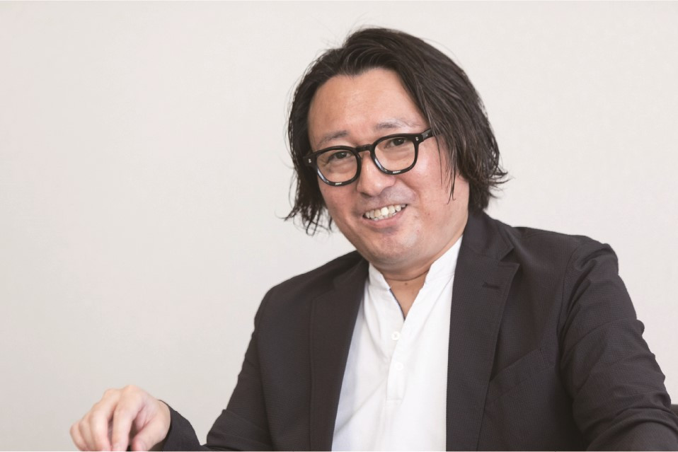 眼鏡をかけた男性がスーツで微笑んでいる