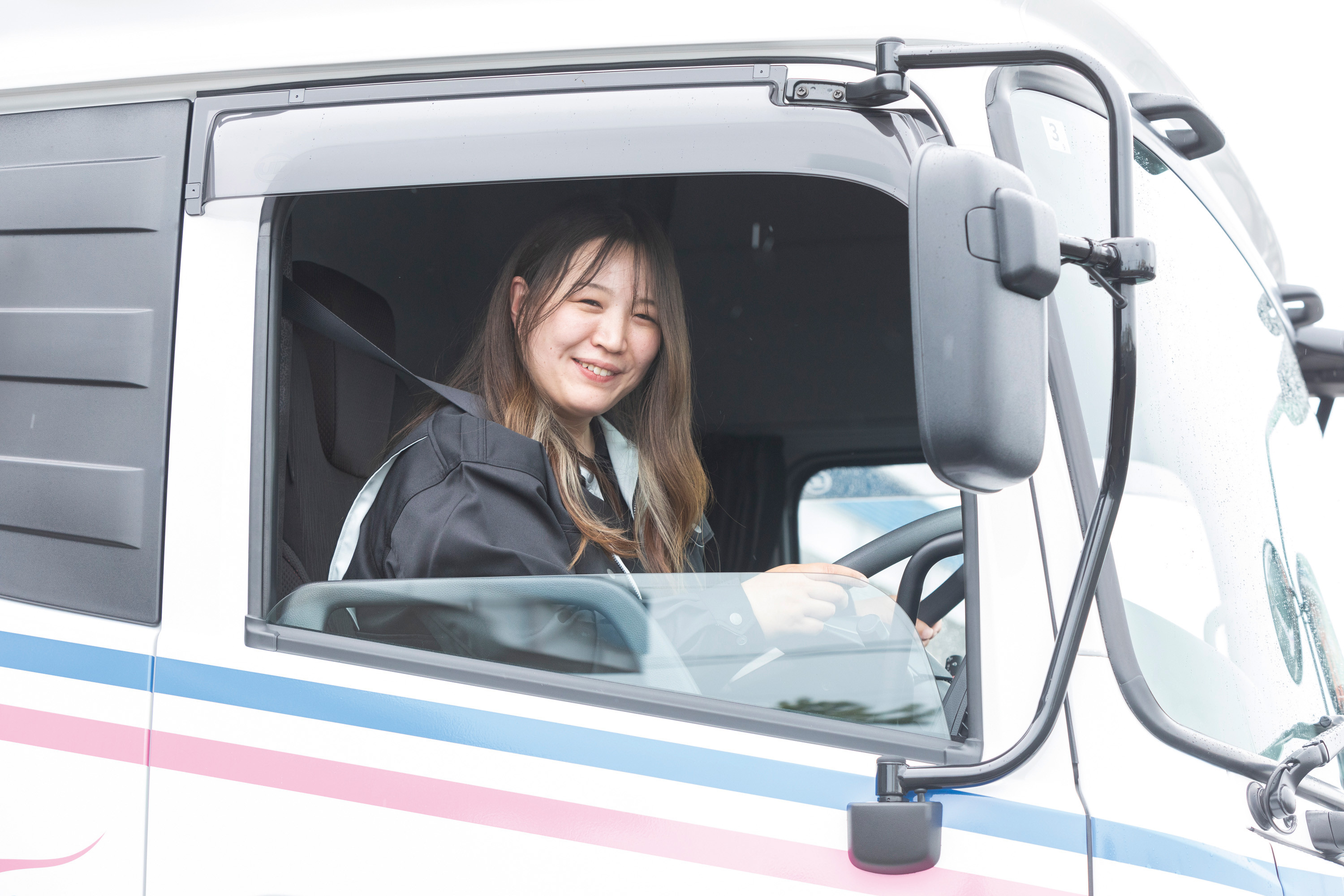 トラックの運転席で笑顔の女性