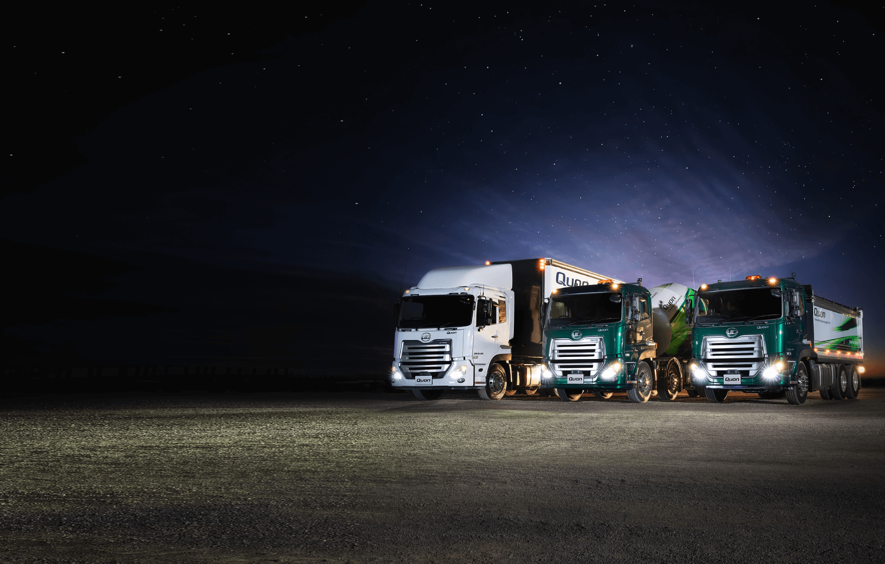 Three semi-trucks parked side by side under a night sky with stars.