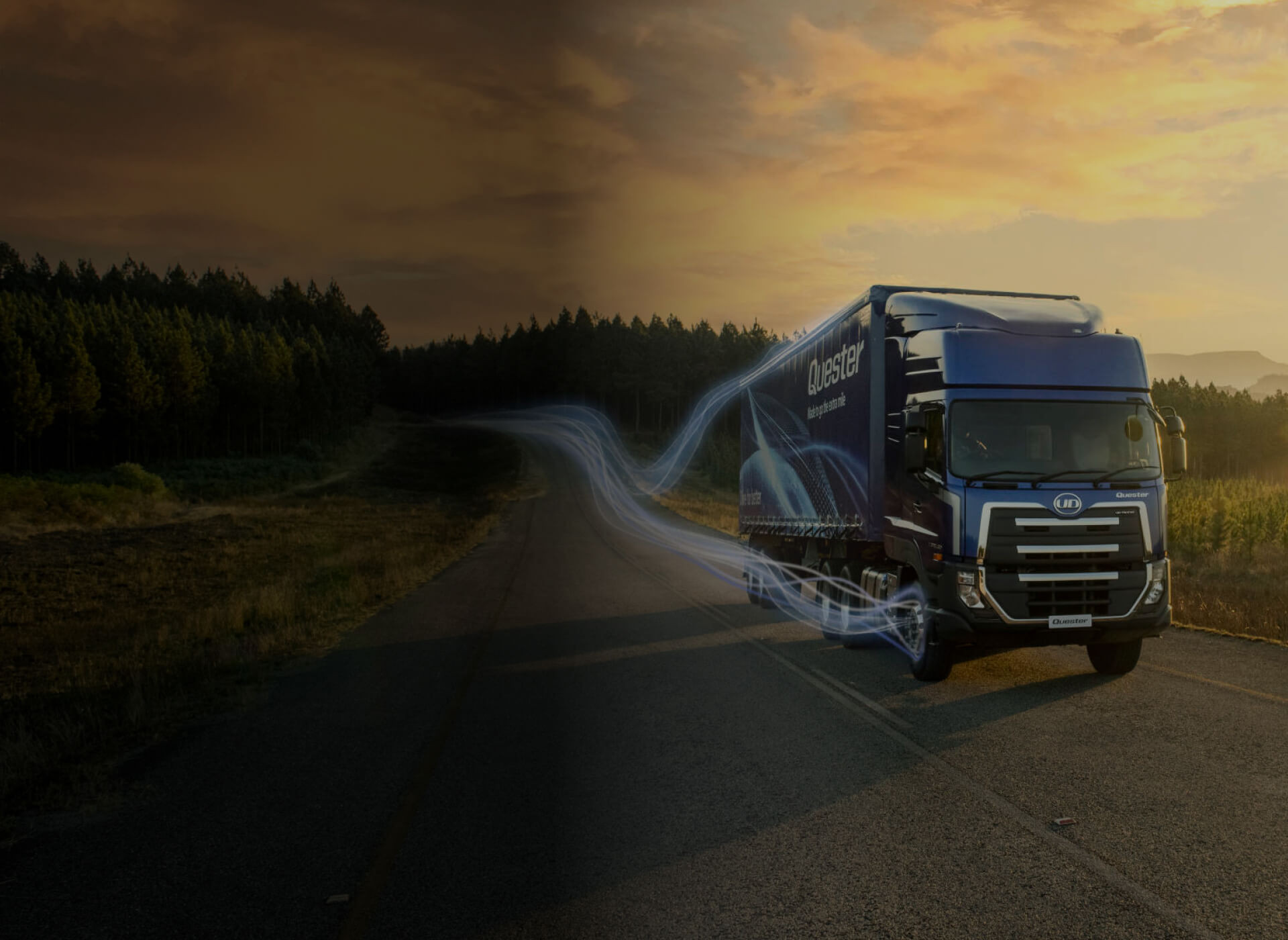 Xe tải màu xanh chạy trên đường vắng lúc hoàng hôn, khung cảnh có rừng cây hai bên.