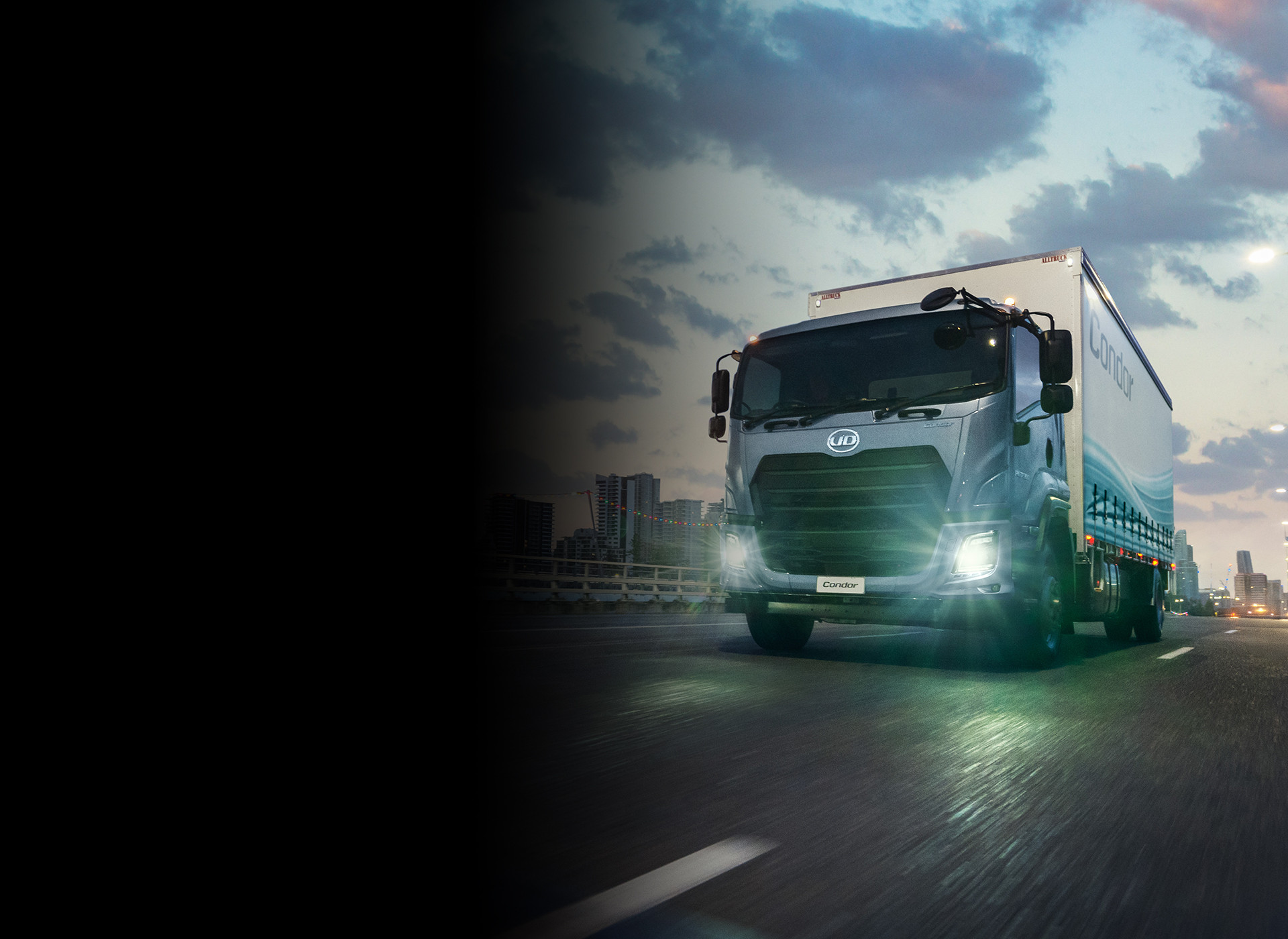 Truck driving on city road at dusk with headlights on