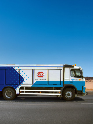 شاحنة صهريج أزرق وأبيض على طريق بجانب صحراء وتحت سماء صافية