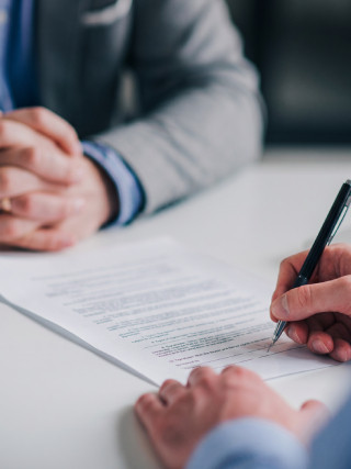 شخصين جالسين على مكتب، واحد منهم يوقّع ورقة رسمية