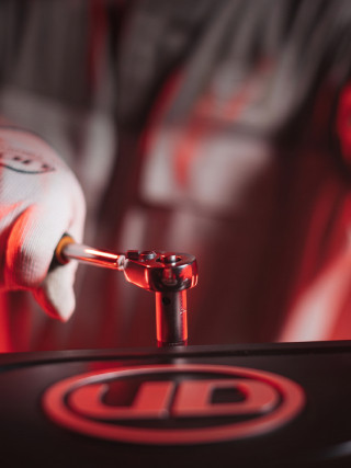 يد في قفاز تستخدم مفتاح ربط على سطح عليه شعار أحمر وأسود