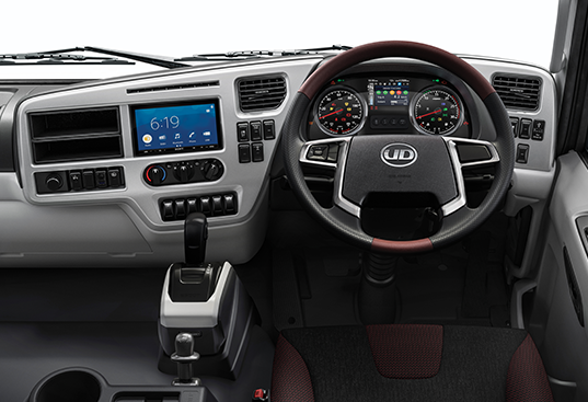 Modern truck dashboard with steering wheel, digital screen, and control buttons.