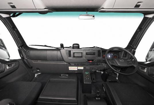 Truck cabin interior with steering wheel, dashboard, and control panels.