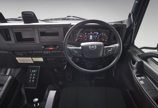 Modern truck dashboard and steering wheel with illuminated instrument panel.